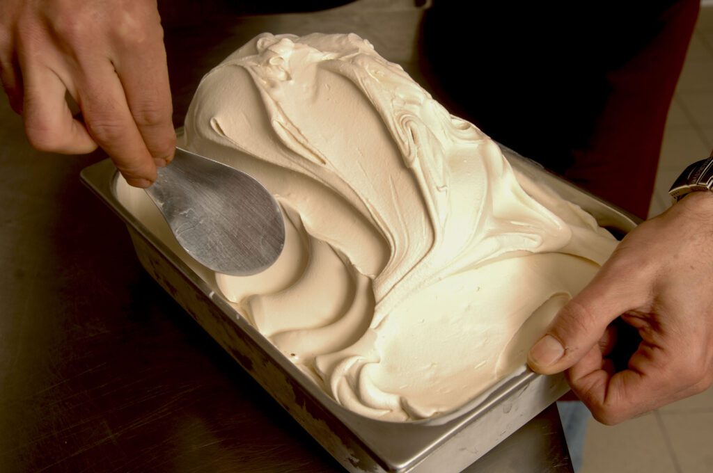 person smoothing gelato in a metal container