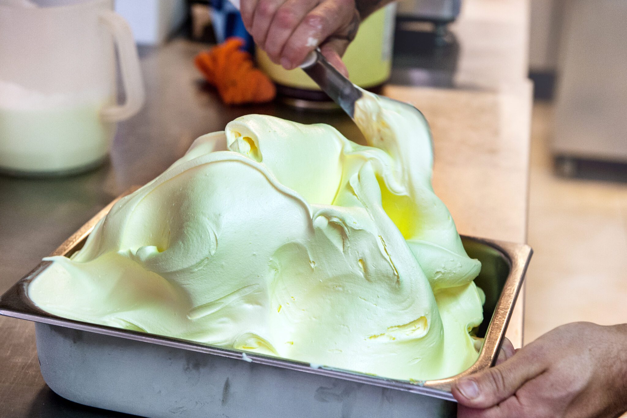 person adding a fresh batch of gelato to a metal tub